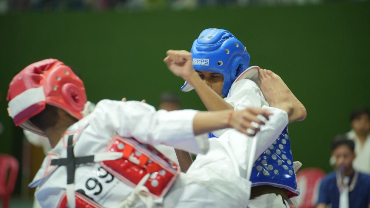 Two young karateka in helmets and body guards exchanging techniques at a KKFI tournament